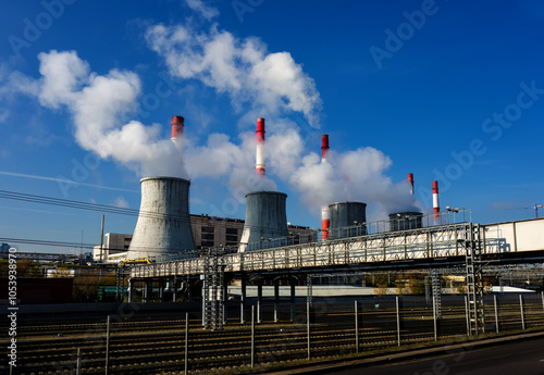 Smoking pipes of power plants against the blue sky. Puffs of steam over cooling towers.