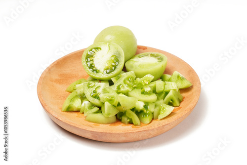 Whole and sliced green tomatoes (Solanum lycopersicum) on a wooden plate against a white background. The photo captures the fresh, juicy, and crisp texture of the slices.