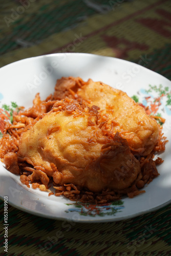 A plate of fried banana or Pisang Goreng (Musa acuminata × balbisiana), an Indonesian favorite snack. Sliced kepok bananas coated in batter and fried until crispy, offering a sweet, delightful taste.