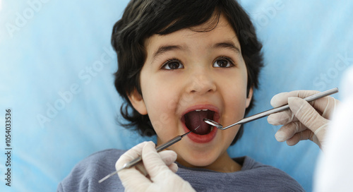 Cute arab boy sitting at dental chair with open mouth during oral checking up with doctor. Visiting dentist office. Stomatology concept
