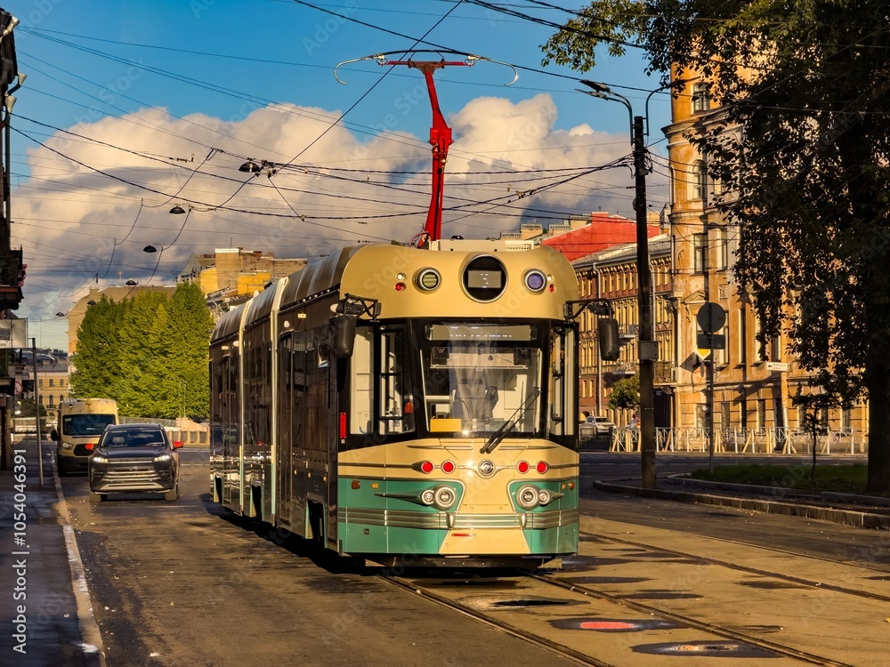Obraz premium A vintage-inspired tram travels down a quiet street in Saint Petersburg, illuminated by the warm afternoon sunlight. The tram retro design harmonizes with the historic architecture of the city
