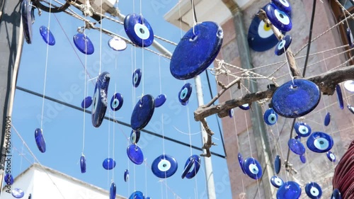 Turkish amulets against the evil eye hanging on a tree branch against a blue sky. Horizontal slow motion