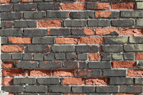 macro close-up of dark gray orange red spalled weathered old brick wall rough texture background photo