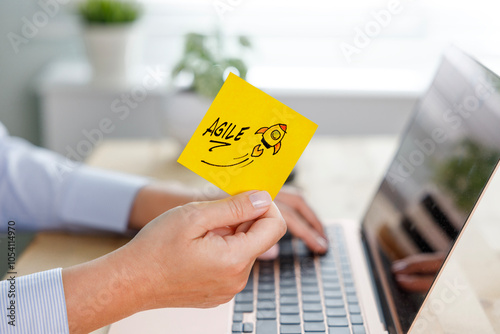 The word Agile and rocket symbol on a yellow adhesive note