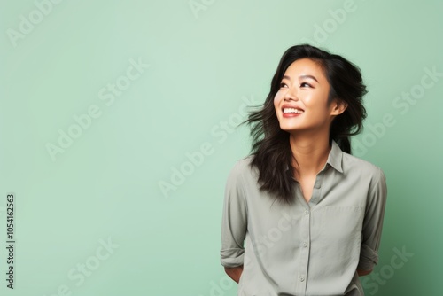 Portrait of a joyful asian woman in her 30s sporting a breathable hiking shirt over solid pastel color wall