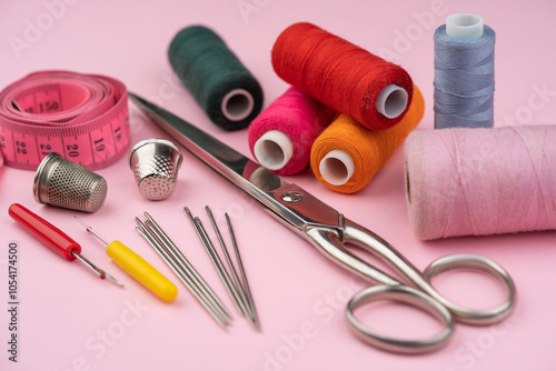 various tailor accessories and tools for tailoring on a pink background photo