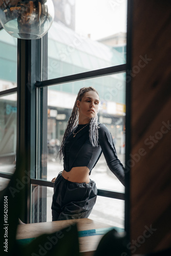 Free Download Fashion portrait of an informal girl with dreadlocks and piercings in a gray top behind the bar in a cafe restaurant - GFXLoad