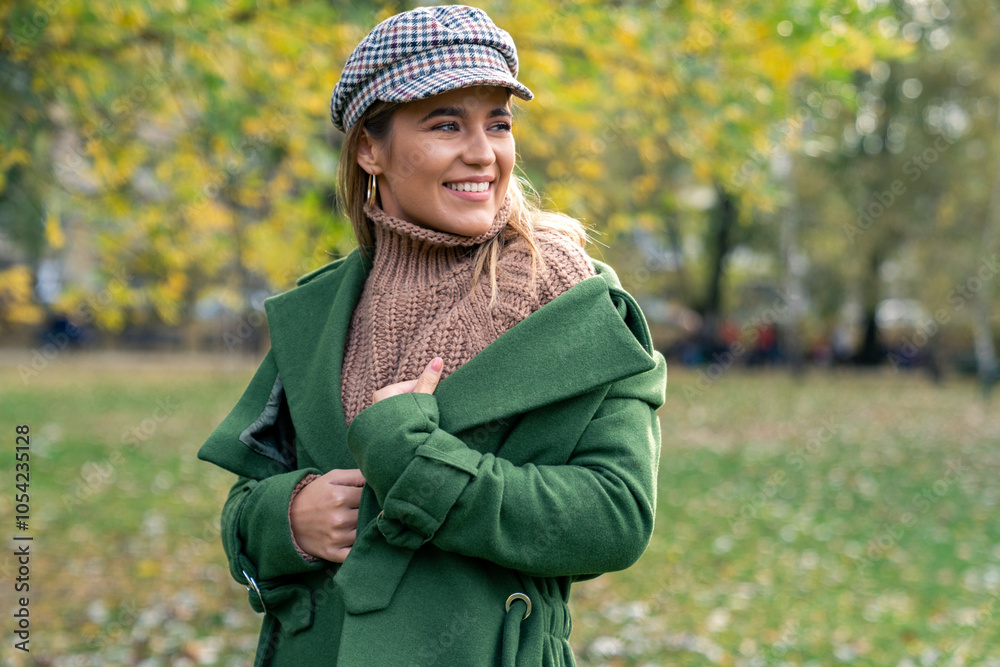 A cheerful Caucasian woman embraces the cool weather, smiling as she strolls through a leaf-strewn park, decked out in cozy green autumn attire. A cheerful Caucasian woman embraces the cool weather, smiling as she strolls through a leaf-strewn park, decked out in cozy green autumn attire.
