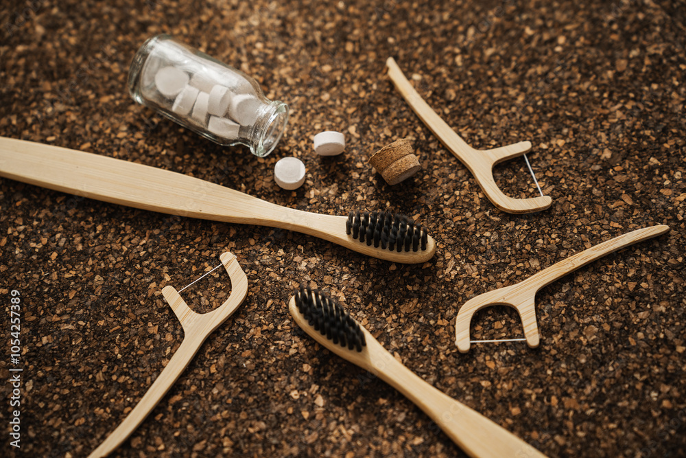 Obraz premium Bamboo Toothbrush, Floss Picks and Toothpaste Tablets on Cork Surface