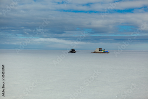Winter Landscape Featuring Snowmobile and Ice Sled Under Cloudy Sky