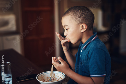 Enjoy, child and lick fingers for eating food in home with empty bowl, nutrition and healthy development at table. African kid, diet or delicious meal in house for lunch, dinner or cuisine with water photo