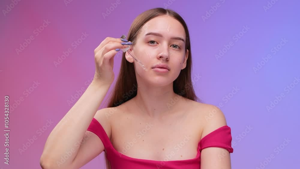 A beautiful young woman is applying a skin moisturizing serum to her face. Cosmetology and professional skin care. A beautiful young woman is applying a skin moisturizing serum to her face. Cosmetology and professional skin care.
