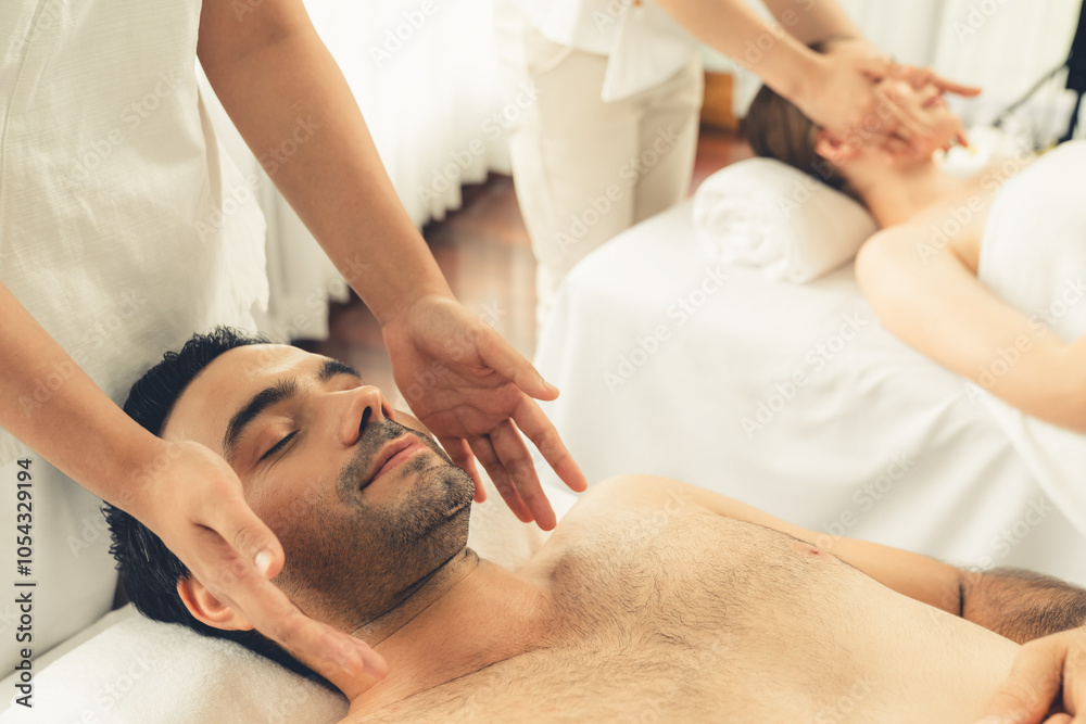 Caucasian couple enjoying relaxing anti-stress head massage and pampering facial beauty skin recreation leisure in dayspa modern light ambient at luxury resort or hotel spa salon. Quiescent Caucasian couple enjoying relaxing anti-stress head massage and pampering facial beauty skin recreation leisure in dayspa modern light ambient at luxury resort or hotel spa salon. Quiescent