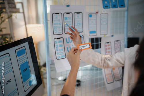 Web designers improving ux and ui of mobile app during a meeting, adding new features and functionalities