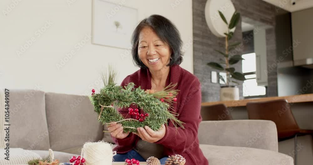 Smiling woman crafting Christmas wreath at home, enjoying festive creativity Smiling woman crafting Christmas wreath at home, enjoying festive creativity