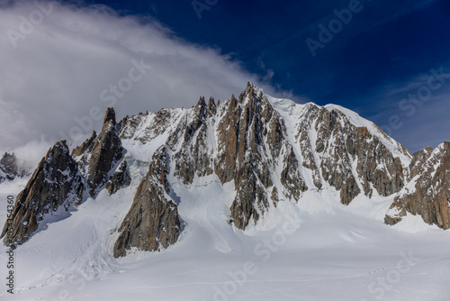 Snow covered mountains and rocky peaks of the Alps from the sky way between Chamonix and Courmayeur in Italy and France Alps. Dent du Gigante rocky towering peak and glacier at the bottom of Montblanc