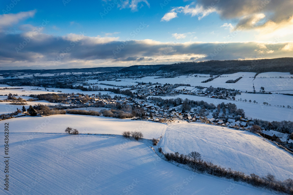 Aerial view of a small German mountain village covered by heavy snow at sunset. Germany.