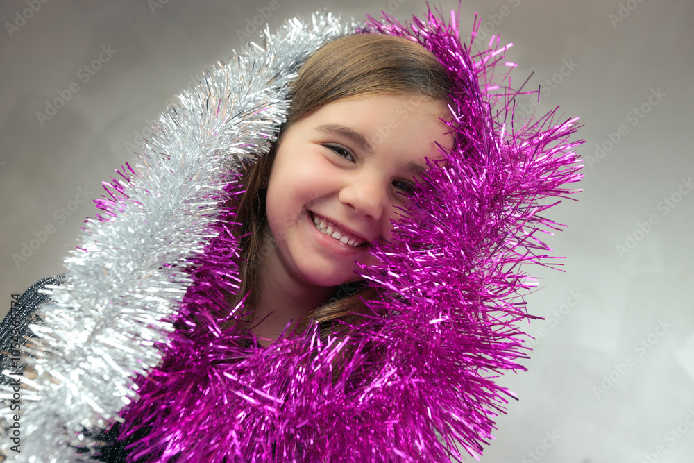Cute little girl with funny expression playing with the tinsel. Christmas decoration Cute little girl with funny expression playing with the tinsel. Christmas decoration