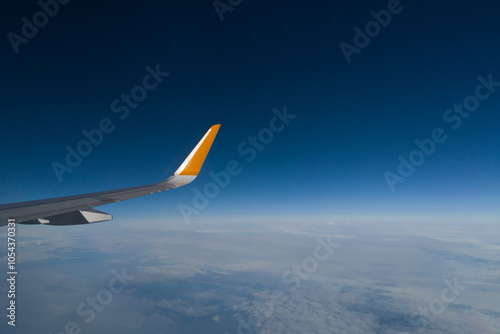 Beautiful skyscape with gradient sky and horizon, clean blue sky, sun, sunbeams as layout with copy space.Ground underneath, part of plane, aircraft wing