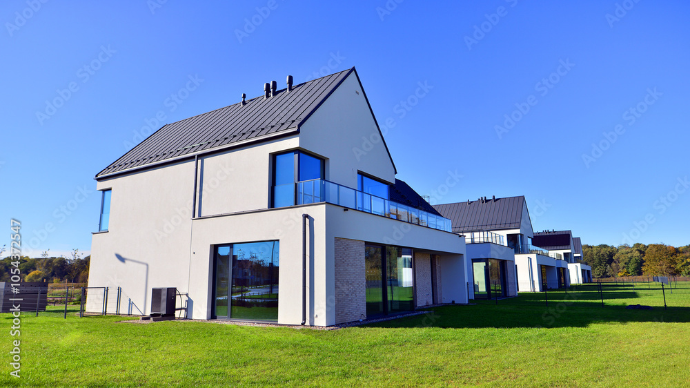 New elegant modern single family house. Terraced family homes in newly developed housing estate. Facade of a modern house with white walls. Real estate concept, european style. New elegant modern single family house. Terraced family homes in newly developed housing estate. Facade of a modern house with white walls. Real estate concept, european style.
