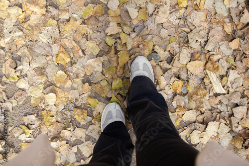 feet in yellow fallen leaves on the floor photo