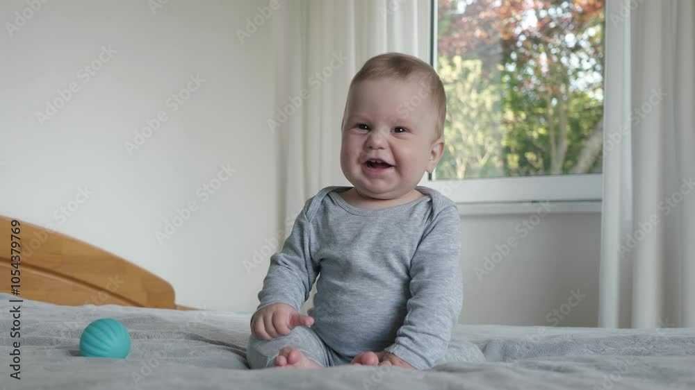Joyful and lively baby sits comfortably on a cozy bed, gazing with curiosity at the camera. Smiling infant enveloped in a soft, warm, and inviting atmosphere filled with love and comfort Joyful and lively baby sits comfortably on a cozy bed, gazing with curiosity at the camera. Smiling infant enveloped in a soft, warm, and inviting atmosphere filled with love and comfort