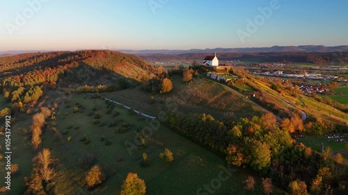 Aerial footage of flight towards lonely chapel (Wurmlinger Kapelle) on a hill at sunset photo