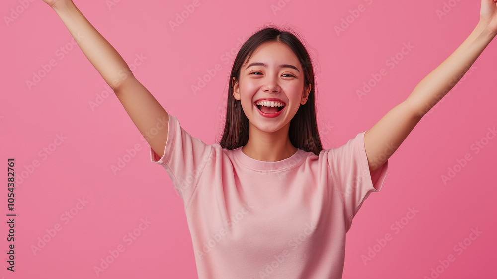 Cheerful woman with arms raised, smiling joyfully against a pink background, expressing happiness, freedom, and positivity. Cheerful woman with arms raised, smiling joyfully against a pink background, expressing happiness, freedom, and positivity.