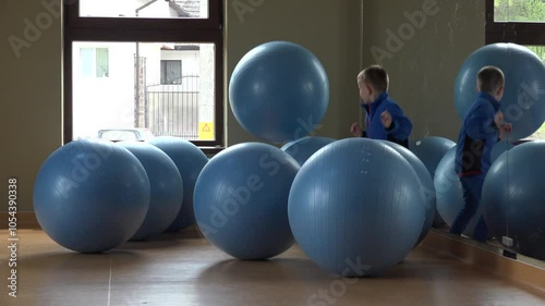 Little boy plays with big balls at the gym