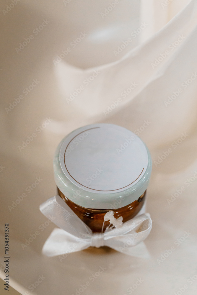Elegant jar of honey with a soft blue lid and a delicate white ribbon on a minimalist plate Elegant jar of honey with a soft blue lid and a delicate white ribbon on a minimalist plate