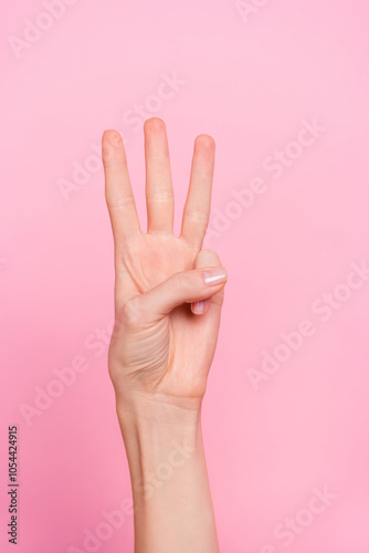 Vertical cropped view of attractive girl hand showing three sign w numb letter isolated over pink pastel color background