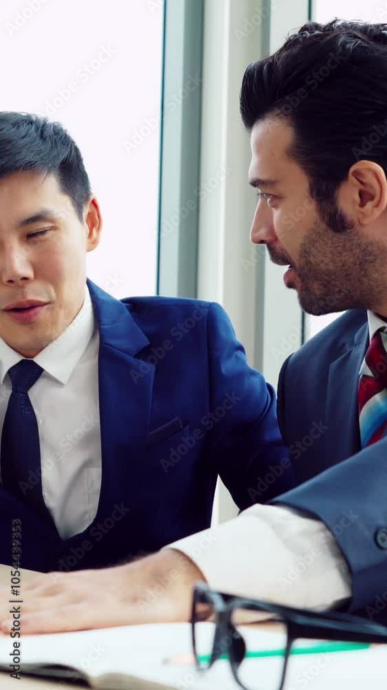 Two business people talk project strategy at office meeting room. Businessman discuss project planning with colleague at modern workplace while having conversation and advice on financial data report.