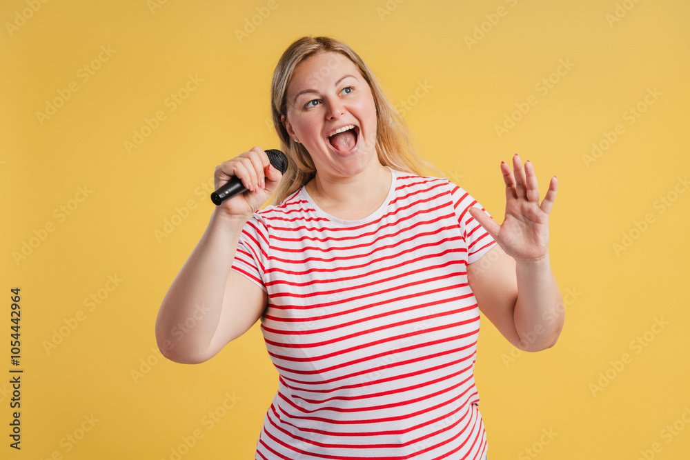 Portrait of plus size young female with microphone against yellow background Portrait of plus size young female with microphone against yellow background