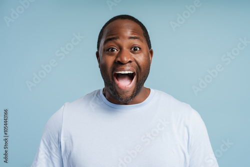 Surprised young African American man posing in studio isolated on blue