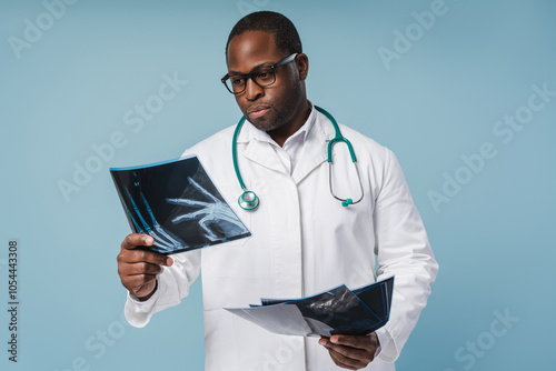 Portrait of African American male doctor looking at a radiography, isolated on blue