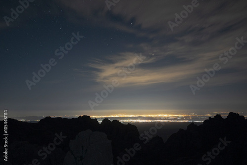 Long exposure shot of Villa Carlos Paz city lights at night, under a sky with stars, seen from the top of Los Gigantes rock massif.  photo