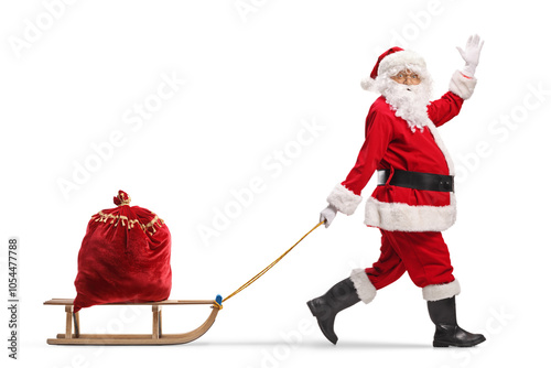Foto Santa Claus pulling a wooden sled with a sack and waving