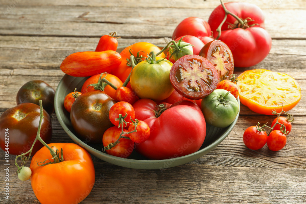Different ripe tomatoes in bowl on wooden table Different ripe tomatoes in bowl on wooden table