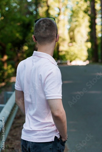 Young Man Standing on a Tree-Lined Pathway in Casual Attire