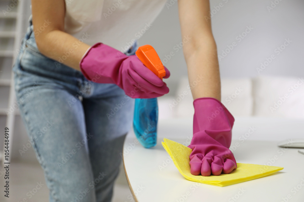 Young woman cleaning table with rag and spray in office, closeup Young woman cleaning table with rag and spray in office, closeup