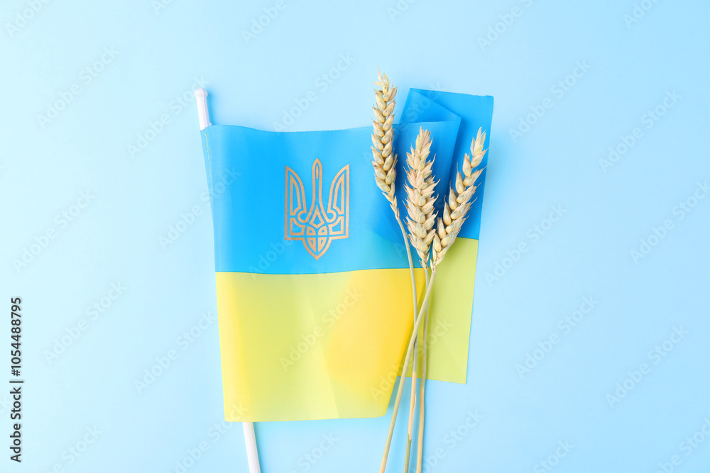 Obraz premium Ears of wheat and Ukrainian flag on light blue background, top view