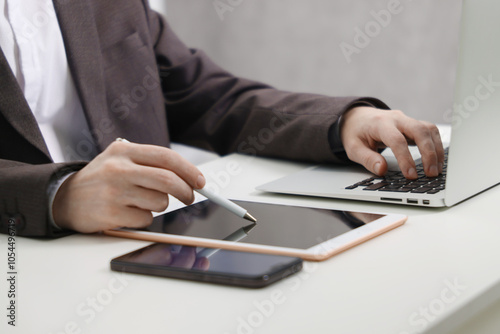 Businessman using different devices at white table indoors, closeup. Modern technology