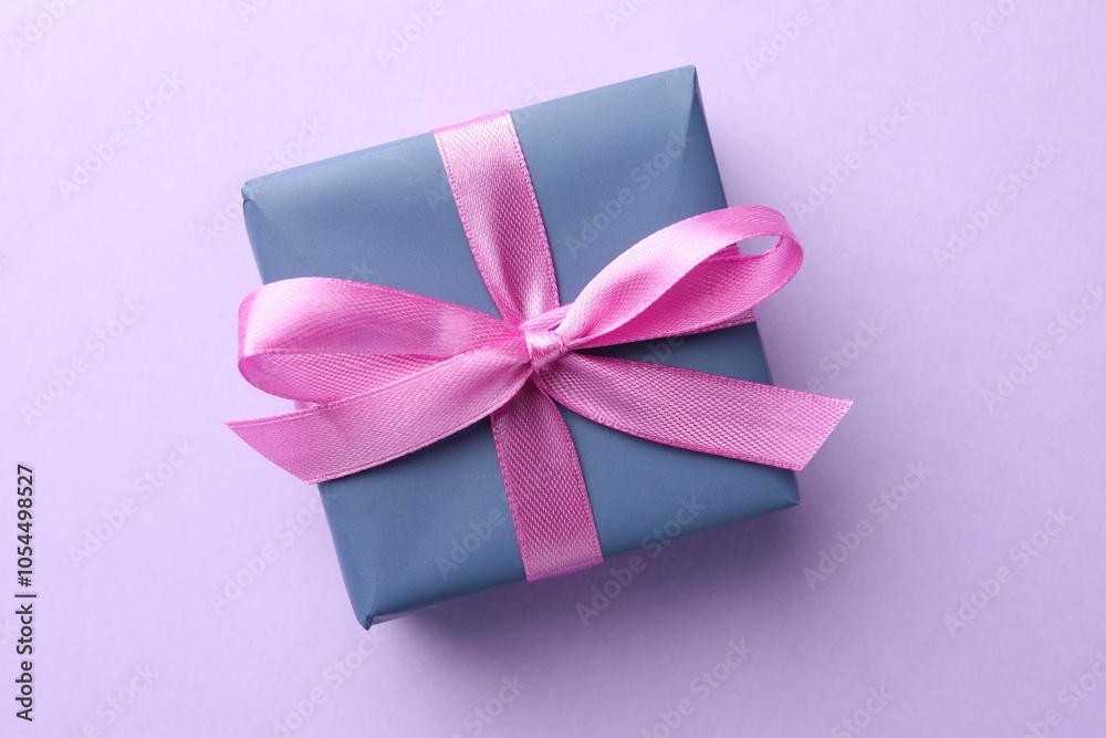 Beautiful gift box with pink bow on violet background, top view Beautiful gift box with pink bow on violet background, top view