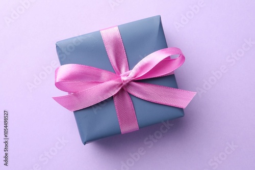 Beautiful gift box with pink bow on violet background, top view