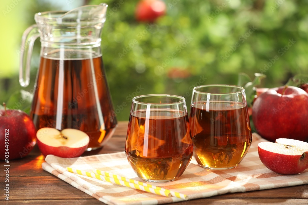 Tasty freshly made apple juice in glasses on wooden table outdoors Tasty freshly made apple juice in glasses on wooden table outdoors
