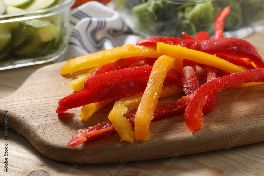 Slices of frozen bell peppers on wooden table, closeup Slices of frozen bell peppers on wooden table, closeup