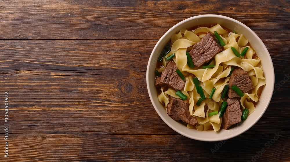 Delicious bowl of beef noodles with vegetables on a rustic wooden table.