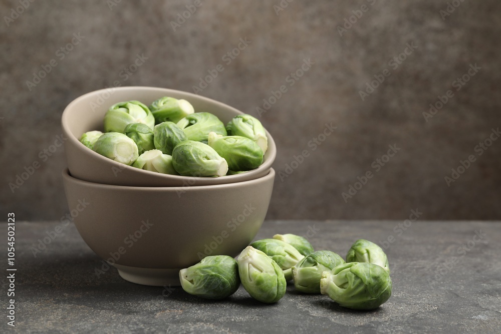 Fresh Brussels sprouts in bowl on grey table, space for text