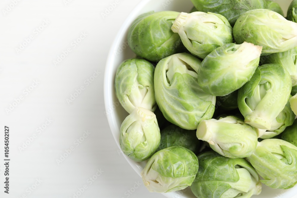 Fresh Brussels sprouts in bowl on white table, top view. Space for text Fresh Brussels sprouts in bowl on white table, top view. Space for text