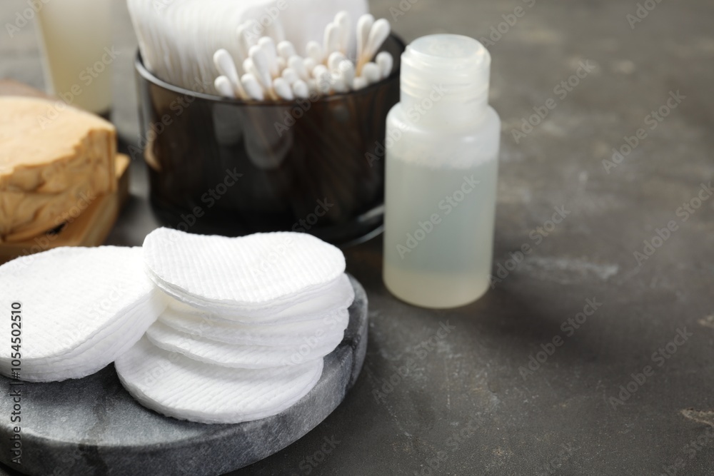 Many cotton pads and other toiletries on grey textured table, closeup Many cotton pads and other toiletries on grey textured table, closeup